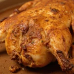 Roasted whole chicken with crispy golden skin on a platter.