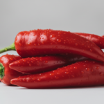 Rote Chilischoten mit Wassertropfen auf weißer Unterlage.