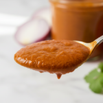 Spoonful of rich tomato sauce with fresh ingredients.