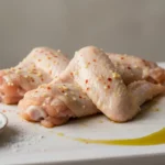 Hähnchenflügel mit Zitronenhälfte, Öl und Salz