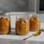 Drei Gläser mit orangefarbener Sauce und Scheiben auf Marmortisch