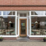 Gemütliches Café in Backsteinfassade mit großen Fenstern.