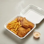 Frittiertes Hähnchen mit Pommes in Box, Soße daneben.