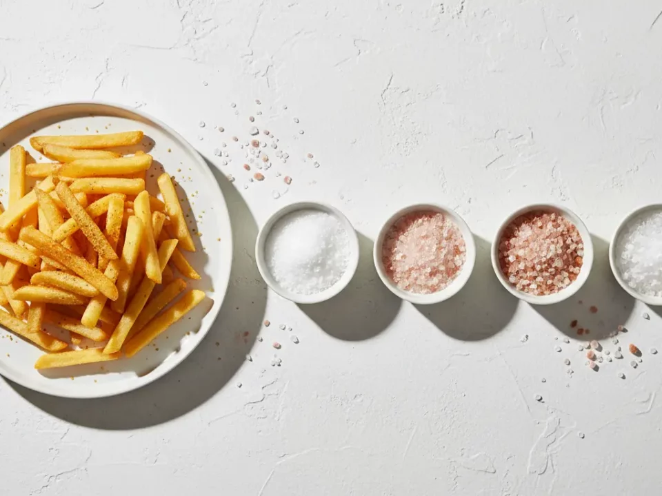 Pommes Frites auf Teller neben Salzsorten.
