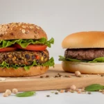 Zwei Burger mit Gemüse auf Holzbrett.
