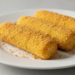Drei knusprige Kroketten auf weißem Teller.