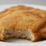 Knusprig paniertes Schnitzel mit Zitronenscheibe.