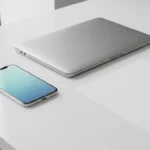 Silbernes Laptop und Smartphone auf weißem Schreibtisch neben QR-Code.