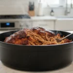 Schwarzer Schmortopf mit zerrissenem Fleisch