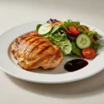 Gegrilltes Hähnchenbrustfilet mit Salat und dunkler Sauce.