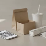 finke-blog275051: Takeaway-Verpackungen neben Smartphone mit QR-Code