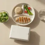 Frische Mahlzeit mit Hähnchen, Reis und Salat auf hellem Tisch.