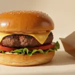 Hamburger mit Käse, Salat und Tomate auf Sesambrötchen.